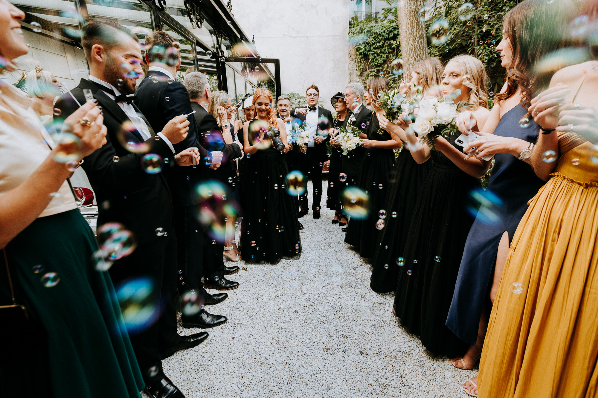 Paris wedding photographer: the guests are waiting for the newlyweds to meet them in the patio and are blowing lots of bubbles in the meantime