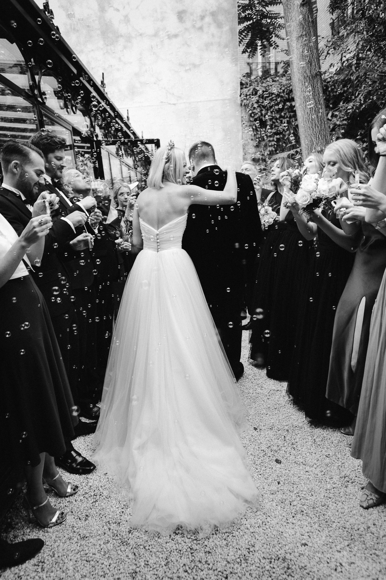 Paris wedding photographer: the guests are waiting for the newlyweds to meet them in the patio and are blowing lots of bubbles in the meantime