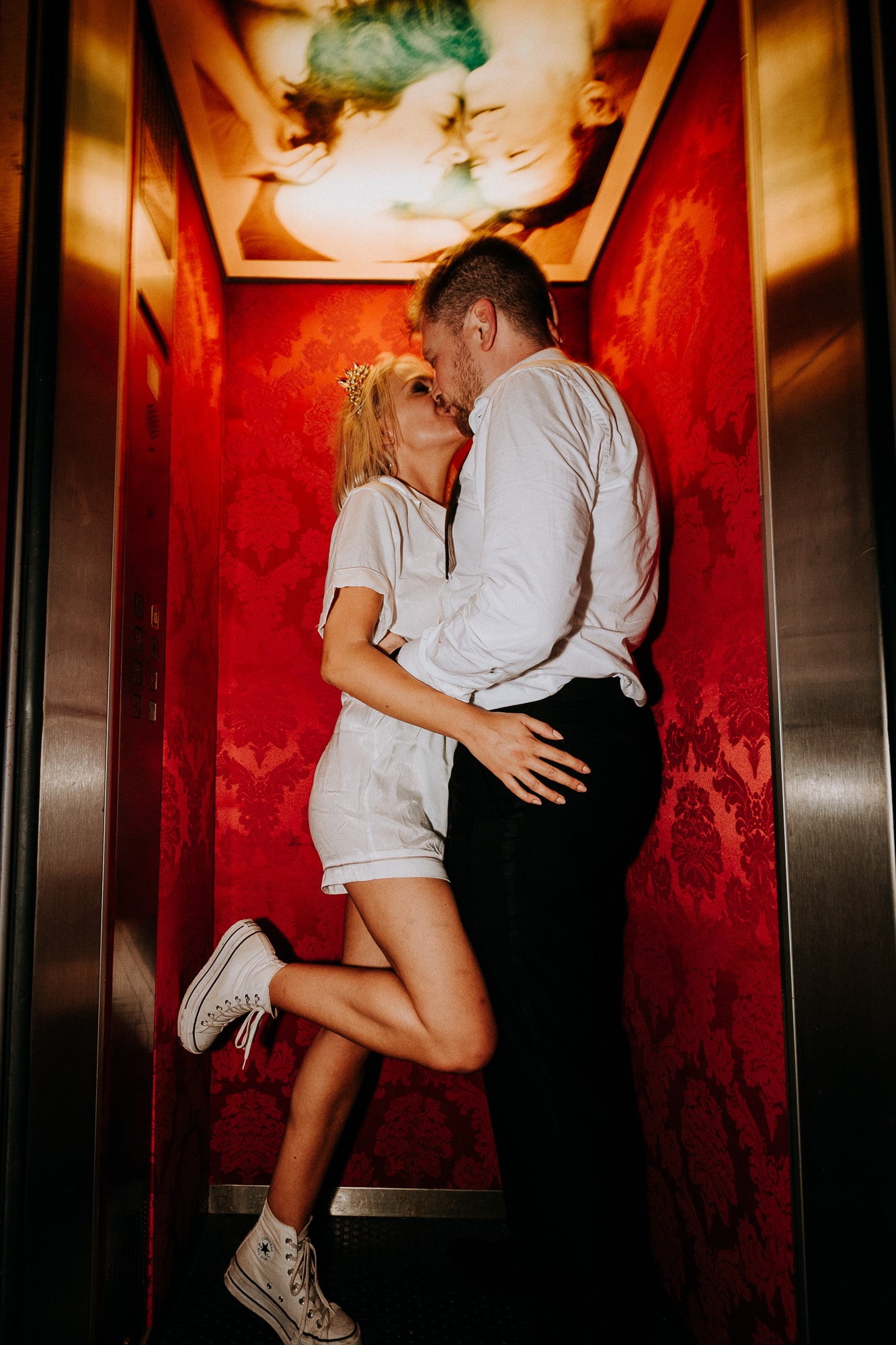 the bride and groom passionately kiss in the lift at the end of their wedding party