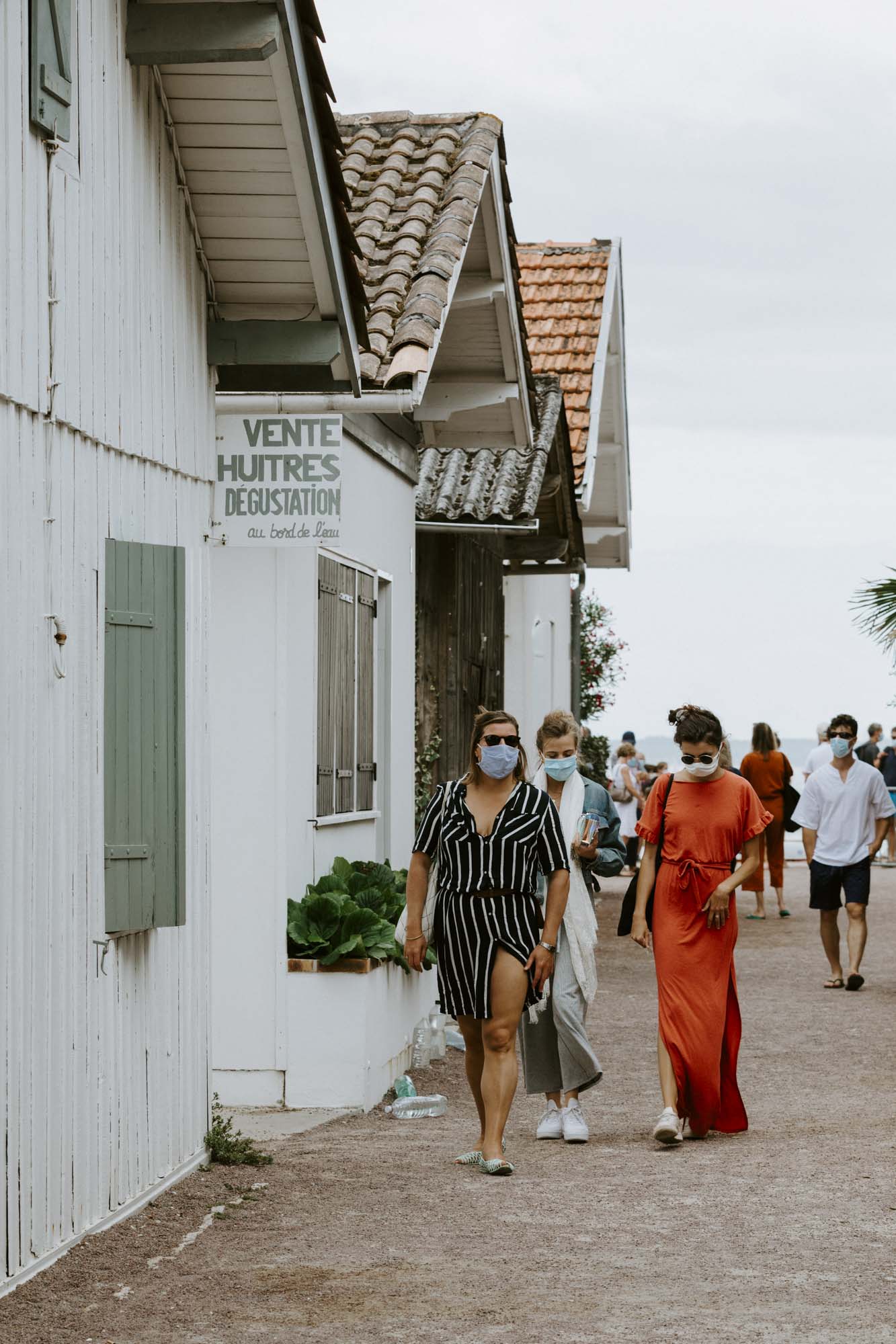 Arcachon wedding photographer: the wedding guests have arrived at Le Canon and are having a stroll alongside the colouful oyster huts