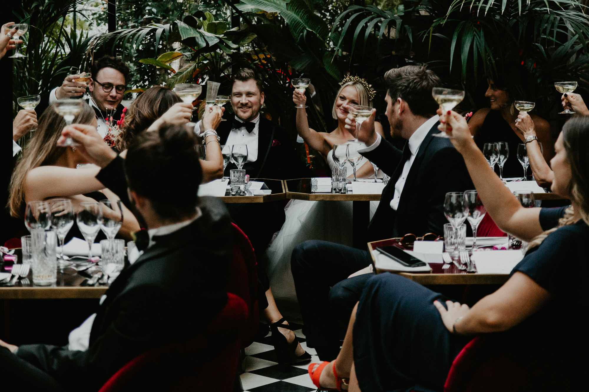 les invités et les mariés portent un toast, assis pour diner dans la véranda du Très Particulier, le bar de l'Hôtel Particulier à Montmartre qui avait été privatisé pour l'occasion