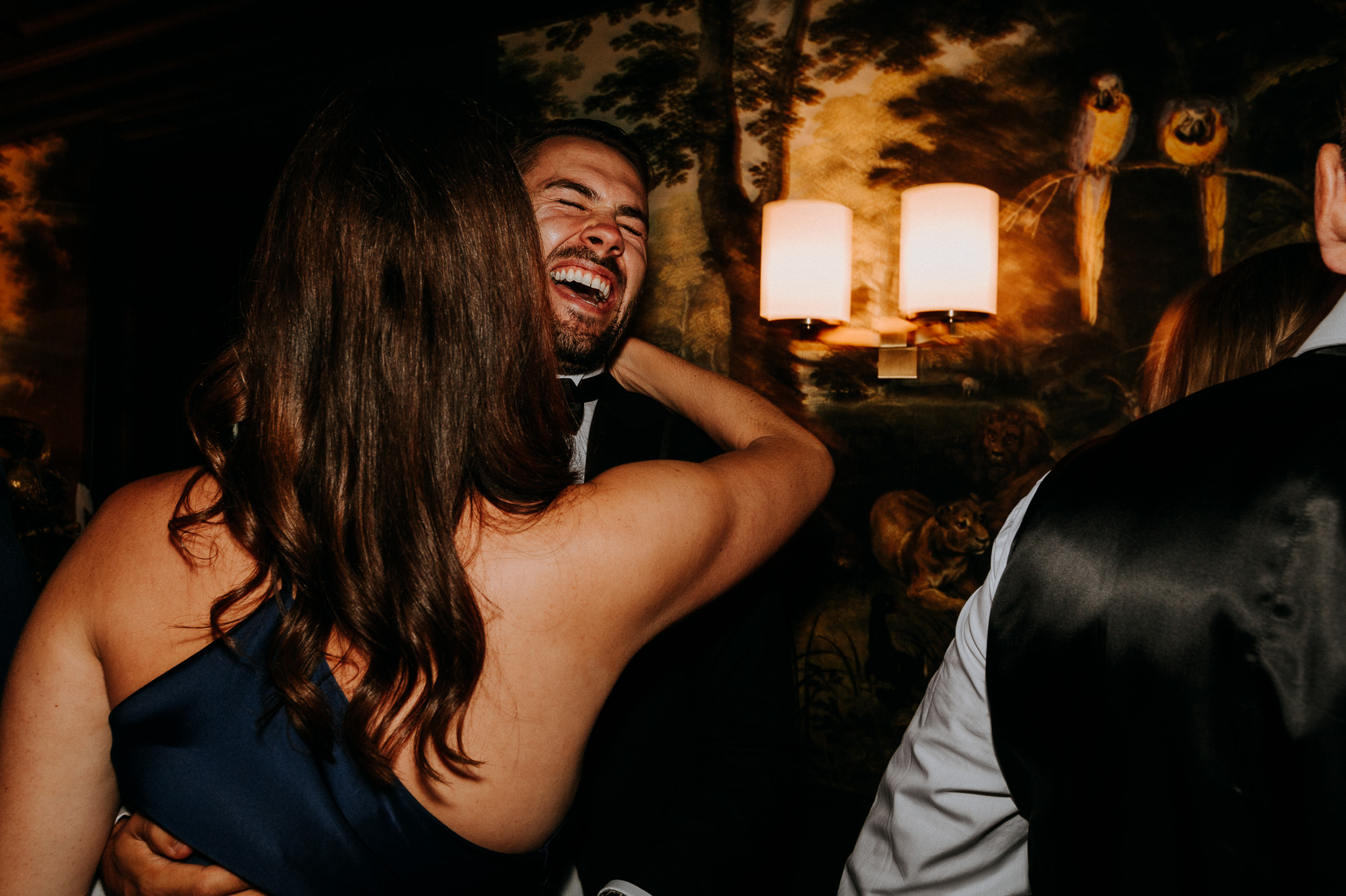 Un invité dansant avec sa femme explose de rire alors qu'elle lui dit quelque chose dans l'oreille