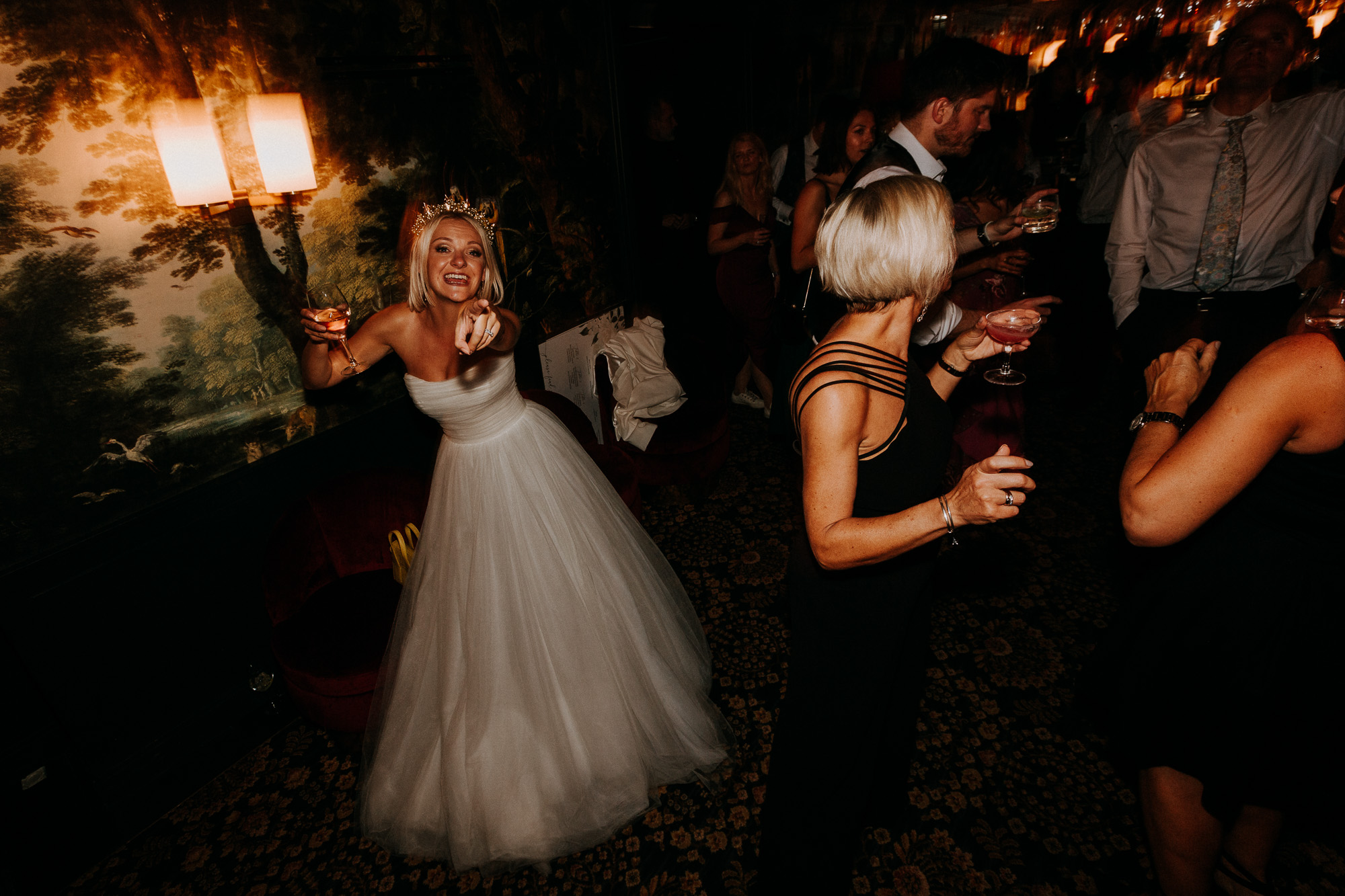 la mariée pointe du doigt la photographe, un verre de vin à la main, en dansant au Très Particulier, le bar de l'Hôtel Particulier à Montmartre