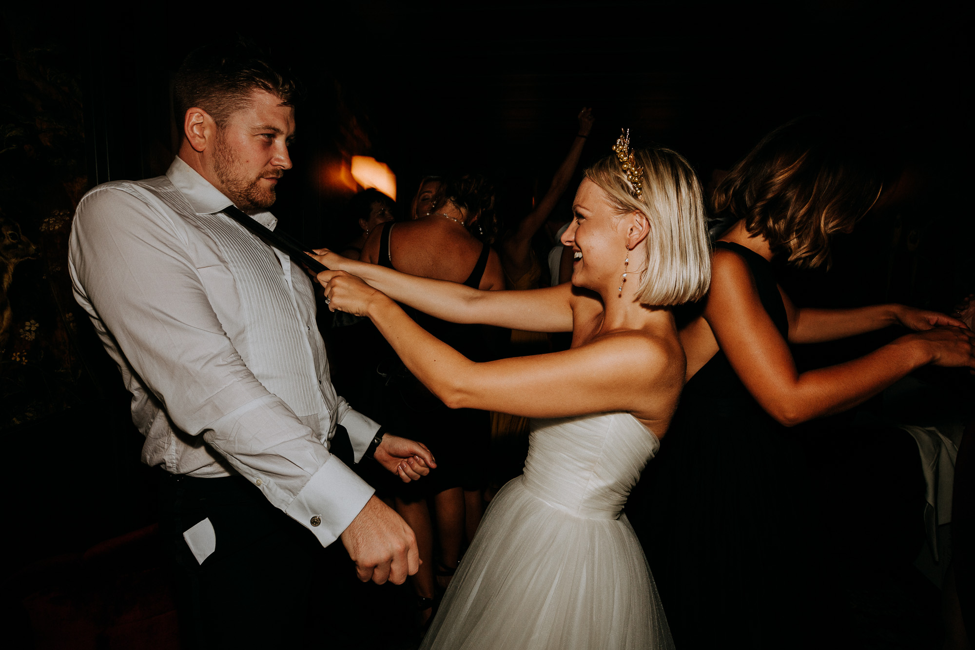 la mariée danse avec son époux, le tenant par la cravate