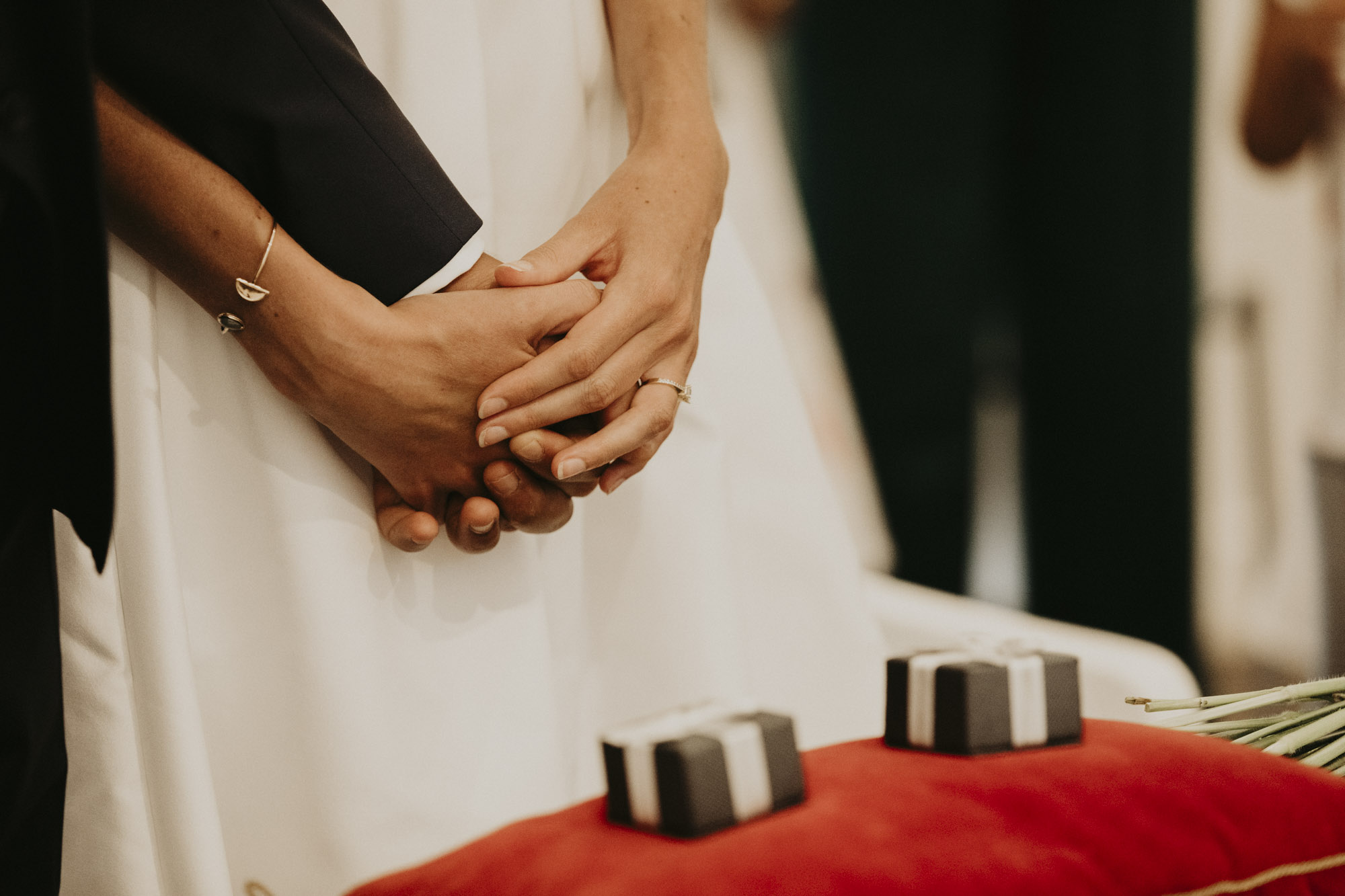 Mariage à Arcachon: gros plan sur les mains enlacées des mariés ainsi que les boites à alliances pendant la cérémonie civile au Pyla-sur-Mer